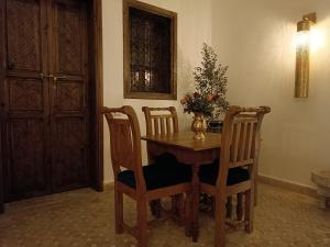 a dining room table with two chairs and a vase with flowers at Riad Beni Sidel in Marrakech