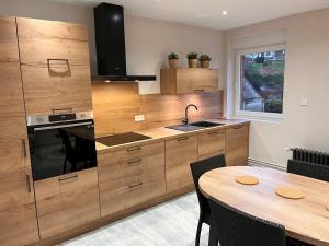 uma cozinha com armários de madeira e uma mesa de madeira em Le Clos Joli em Haybes