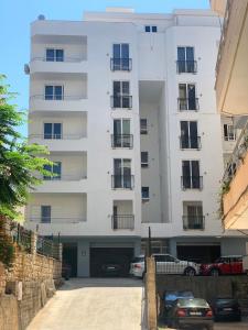 a white building with cars parked in front of it at Dream Apartments Saranda in Sarandë