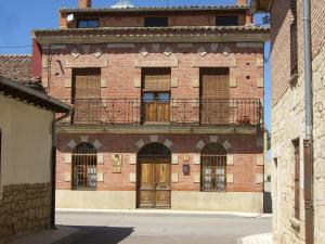 un antiguo edificio de ladrillo con balcón y puerta en Casa Rural El Saúco, en La Vellés