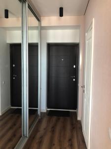 um corredor com portas espelhadas e pisos de madeira em Однокімнатна квартира em Uman
