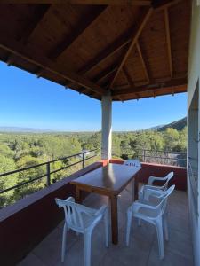 una mesa y sillas en un balcón con vistas en Casas Pura Vida en Villa General Belgrano