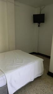 a white bed in a room with a tv on the wall at HOTEL LOS GUADUALES in Barranquilla