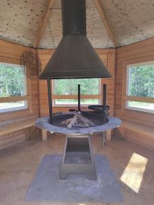 a stove in a wooden cabin with a ceiling at Kangasjoki Riverside Camp in Suomussalmi