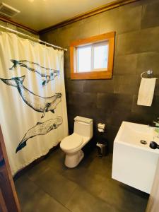 a bathroom with a toilet and a shower curtain at Carpinterito cabaña, ensenada campestre in Puerto Varas