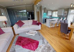 a living room with a white couch and a kitchen at Willow Lakes Lodges in Ashby cum Fenby