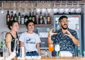 a man and two women standing behind a bar at Veranera Hostel in Estepona
