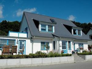 a white house with a black roof and chairs at FW-Seestern-3-Personen in Klein Zicker