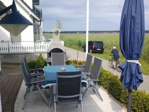 a patio with a table and chairs and a umbrella at FW-Sturmmoewe-4-Personen in Klein Zicker