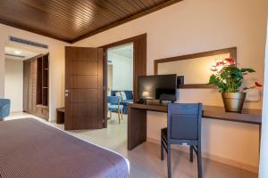um quarto com uma cama e uma secretária com uma televisão em Porto Plaza Hotel em Agios Ioannis Kaspaka