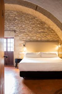 a bedroom with a large bed with a stone wall at Tugasa Convento San Francisco in Vejer de la Frontera