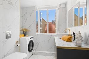 La salle de bains blanche est pourvue d'un lave-linge et d'un lavabo. dans l'établissement Amazing apartment in the center of Helsingør, à Elseneur