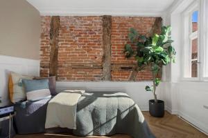 - une chambre avec un lit et un mur en briques dans l'établissement Amazing apartment in the center of Helsingør, à Elseneur