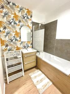 łazienka z wanną, umywalką i lustrem w obiekcie Joli appartement hyper-centre w mieście Alençon