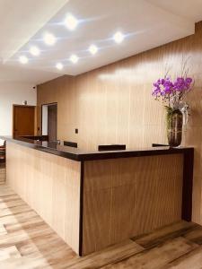 a lobby with a counter with a vase of purple flowers at Leme Plaza Hotel in Leme