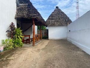 a house with thatched roofs and a bench in the courtyard at La CASETTA A ZANZIBAR B&B in Uroa