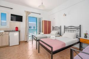 a bedroom with two beds and a kitchen with a balcony at Ornos Apartments in Ornos