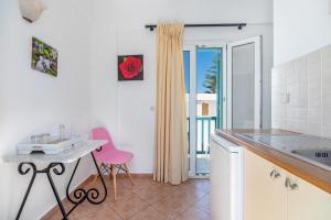 a kitchen with a table and a pink chair at Ornos Apartments in Ornos