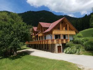 uma grande casa de madeira com um alpendre numa colina em Turistična Kmetija Zgornji Zavratnik em Luče