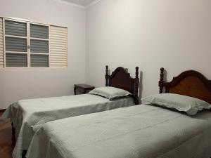 two beds in a white room with a window at Casa espaçosa para lazer em família in Águas de São Pedro