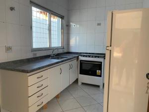 a white kitchen with a sink and a refrigerator at Casa espaçosa para lazer em família in Águas de São Pedro