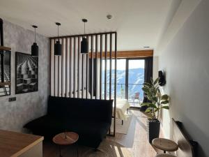 - un salon avec un canapé noir et une grande fenêtre dans l'établissement Stuning views on mountains, gudauri, à Goudaouri