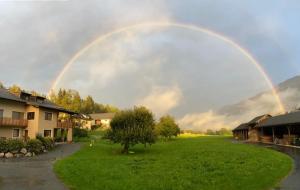 Ein Regenbogen am Himmel über einem grünen Hof in der Unterkunft Rauterhof in Hermagor