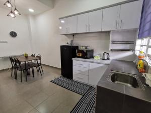 a kitchen with a table and a black refrigerator at De'Sara Damai Homestay, Kuantan in Kuantan