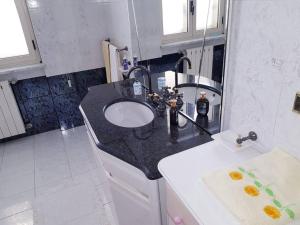 La salle de bains est pourvue d'un comptoir noir et d'un lavabo. dans l'établissement Beach house/Casa mare, à Siderno Marina