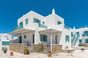 a large white building with green windows and stairs at Ornos Apartments in Ornos