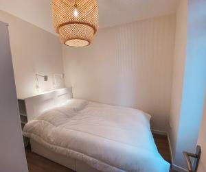 ein Schlafzimmer mit einem weißen Bett und einem Kronleuchter in der Unterkunft TXANPA centre 4 pers in Biarritz