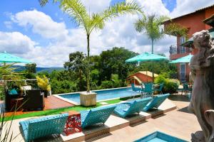 a pool with blue chairs and a palm tree at Pousada Boutique Mirante d'Italia in Pirenópolis