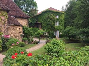 a house covered in ivy with a garden at Logis Hôtel Le Moulin de la Beune in Les Eyzies-de-Tayac