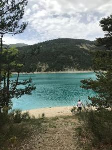 Un homme debout sur une plage près d'un corps d'eau dans l'établissement La maison des Pins, à Saint-Julien-du-Verdon