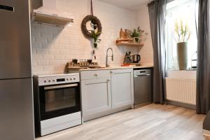 una cocina con armarios blancos y horno negro en Heimat Floral Ferienhaus, en Wadgassen