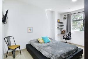 sypialnia z łóżkiem, krzesłem i oknem w obiekcie International House Co-Living w mieście Medellín