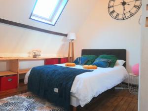 een slaapkamer met een bed met een klok aan de muur bij Le Nid d'hirondelles - Appartement de caractère hypercentre au calme in Bourges