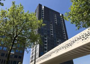 un edificio alto con un árbol delante de él en UNIEK appartement - mooiste en hoogste uitzicht op Antwerpen! - incl gratis parking en Amberes