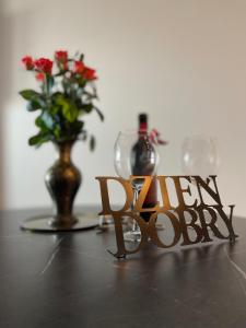 drewniany znak na stole z wazonem kwiatów w obiekcie VISTULA TERRACES 10th floor w Krakowie