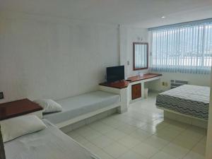 sypialnia z łóżkiem i biurkiem z telewizorem w obiekcie Hotel Aristos Acapulco w Acapulco