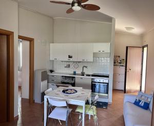 a kitchen with a table with chairs and a ceiling fan at Casa EleGiò - Blue Village 2 in Marina di Pisticci