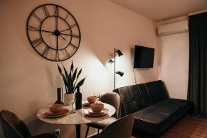 uma sala de estar com uma mesa e um relógio na parede em Studio apartman Mia em Županja