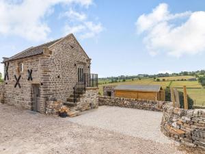 un antiguo granero de piedra con una pared de piedra en Piggledy Cross Barn, en Butterton