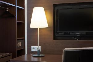 a lamp sitting on a table next to a tv at Villa Hotel Frankfurt by MZ HotelCollection in Frankfurt