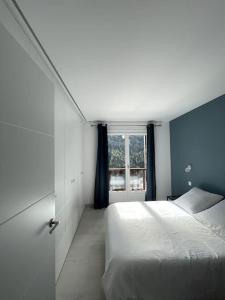 een slaapkamer met een wit bed en een raam bij Soldeu appartement lumineux en face des piste ski HUT08245 in Canillo