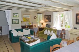 una sala de estar con 2 sofás verdes y una mesa. en Bed & Breakfast Le Moulin Neuf, en Saint-Alvère