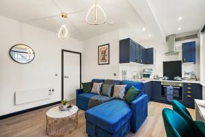 a living room with a blue couch and a kitchen at Stylish Yorkshire Gem - Sleeps 4 - Great Location in Castleford