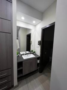 La salle de bains est pourvue d'un lavabo et d'un grand miroir. dans l'établissement Madison Suites, à Cuauhtémoc