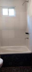 a white bathroom with a tub and a window at Loicas en El Chaltén - Cabaña in El Chalten