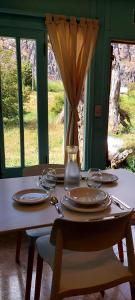 una mesa con platos y un jarrón encima en Loicas en El Chaltén - Cabaña en El Chaltén